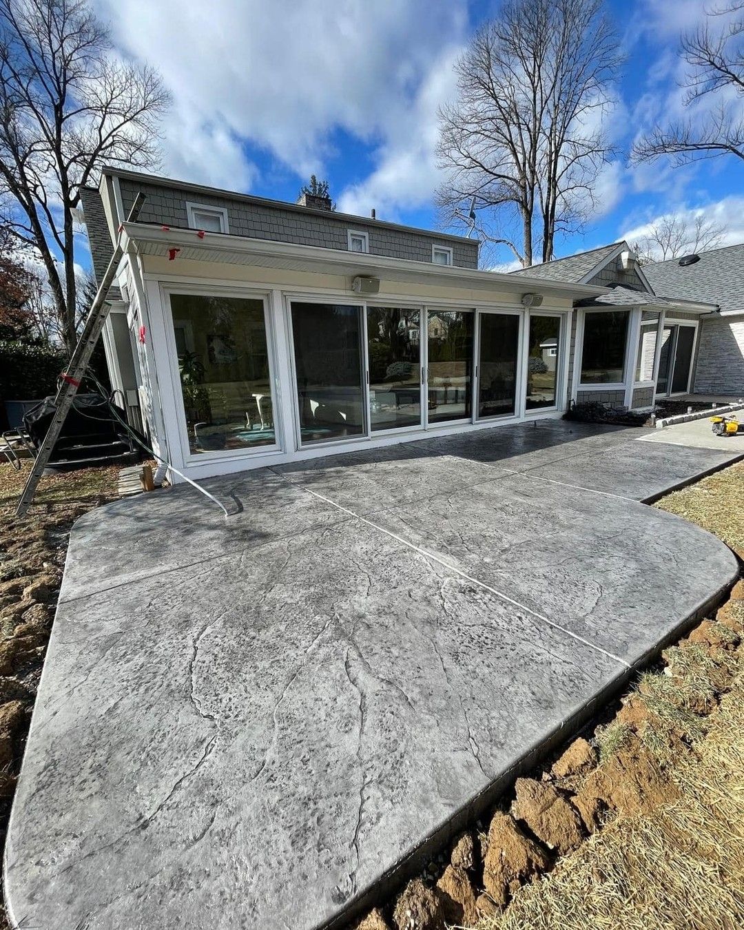 Gray stamped concrete patio wrapping a sunroom