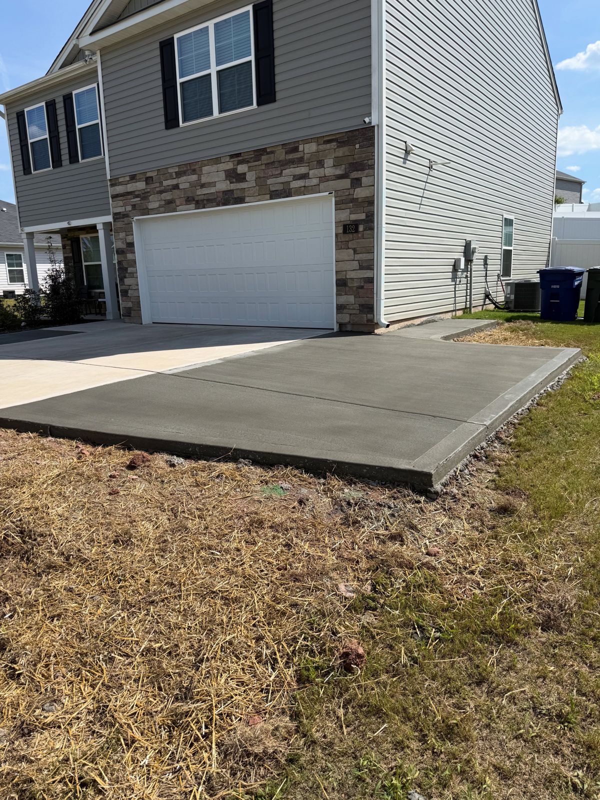 New concrete pad beside a two-story home